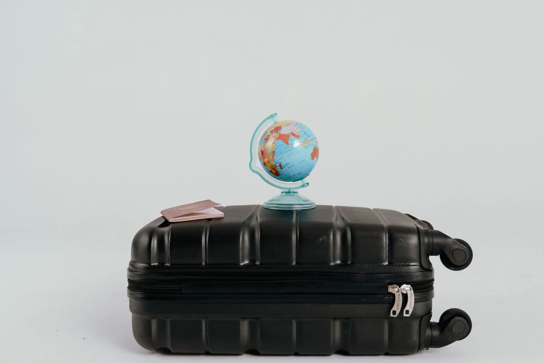 A globe placed on a black suitcase symbolizing global travel and adventure.