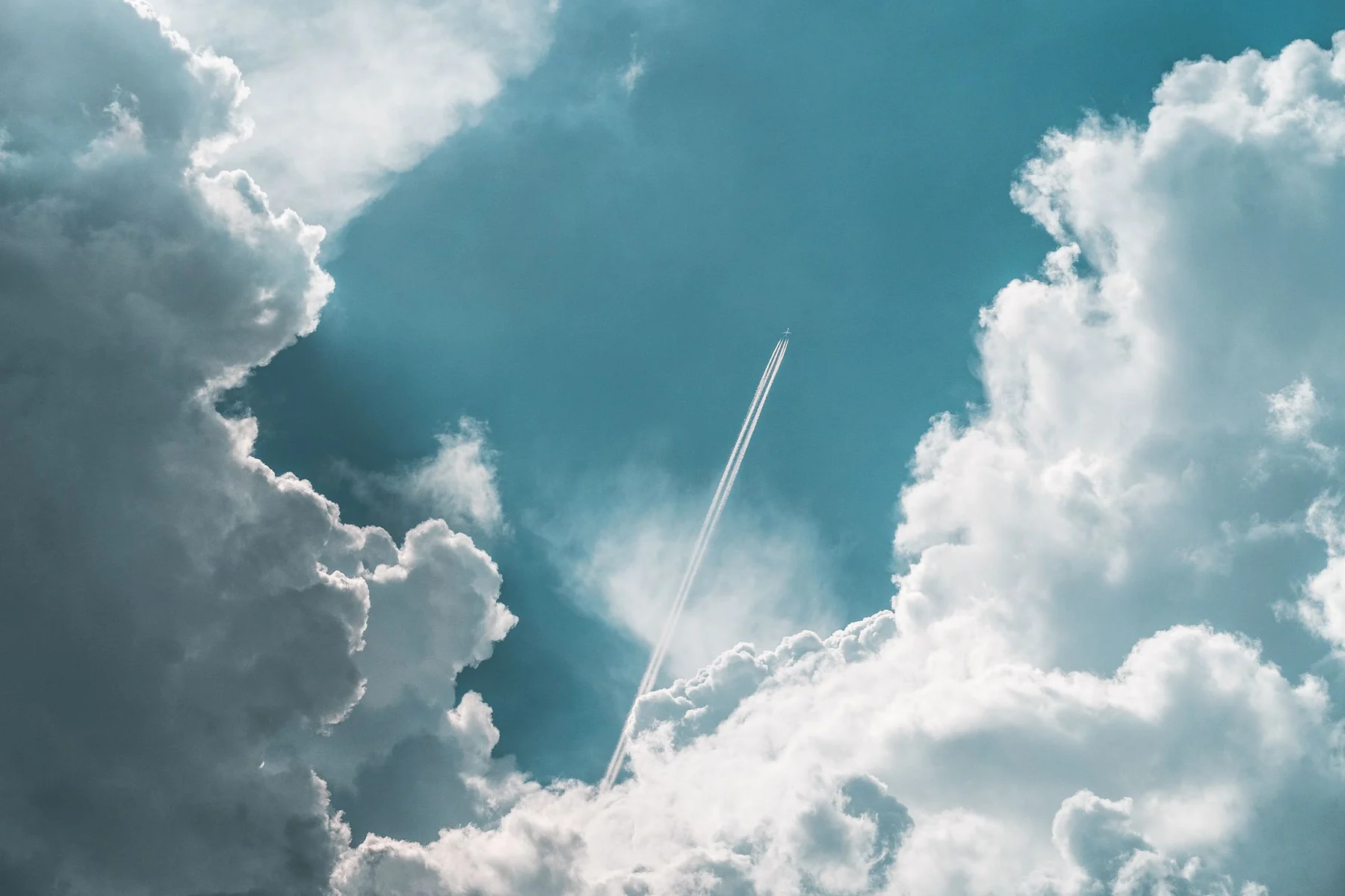 An airplane soars high above Ilmenau, Germany, leaving a trail amidst dramatic clouds.