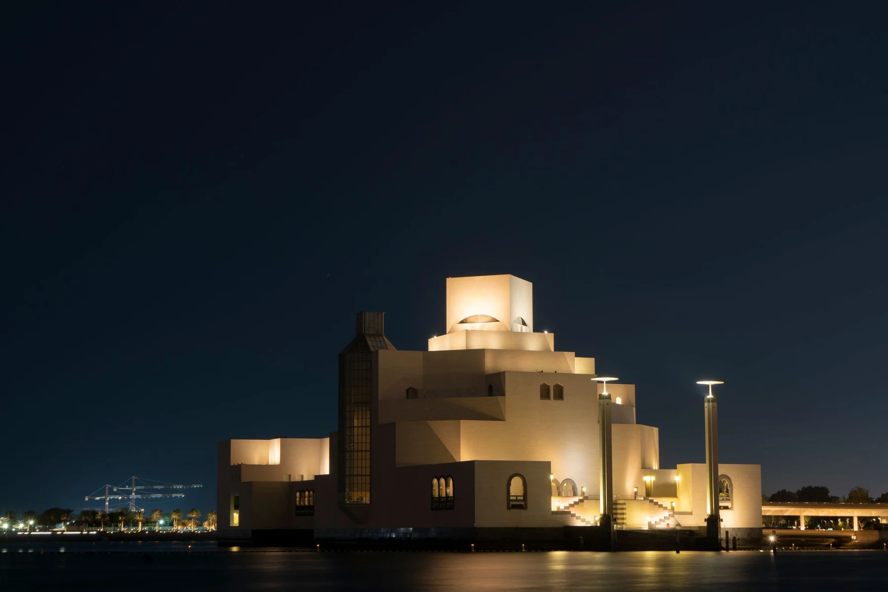 Stunning view of the illuminated Museum of Islamic Art in Doha, Qatar, captured under a clear night sky.