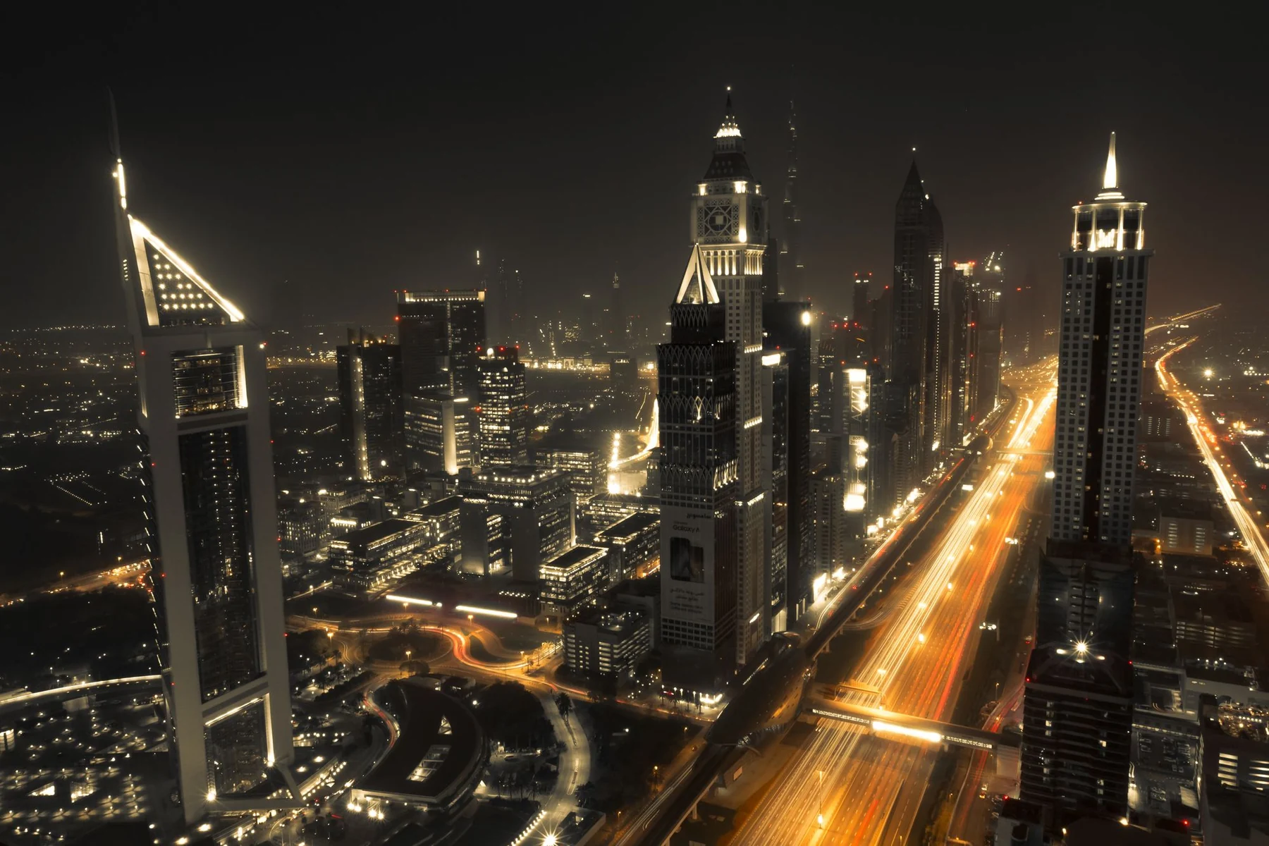 Spectacular night cityscape of Dubai's illuminated skyline featuring iconic skyscrapers and light trails.