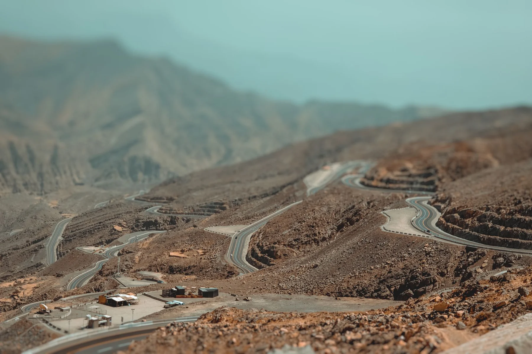 Aerial view of winding roads through the rocky landscape of Jebel Jais in Ras Al-Khaimah, UAE.